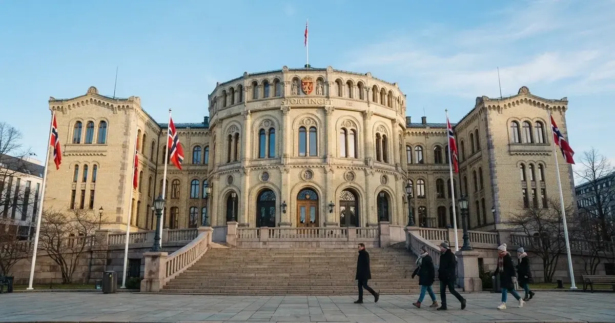 Fasade av en statelig offentlig bygning i lys stein i Oslo med flagg og brede trapper under klar himmel